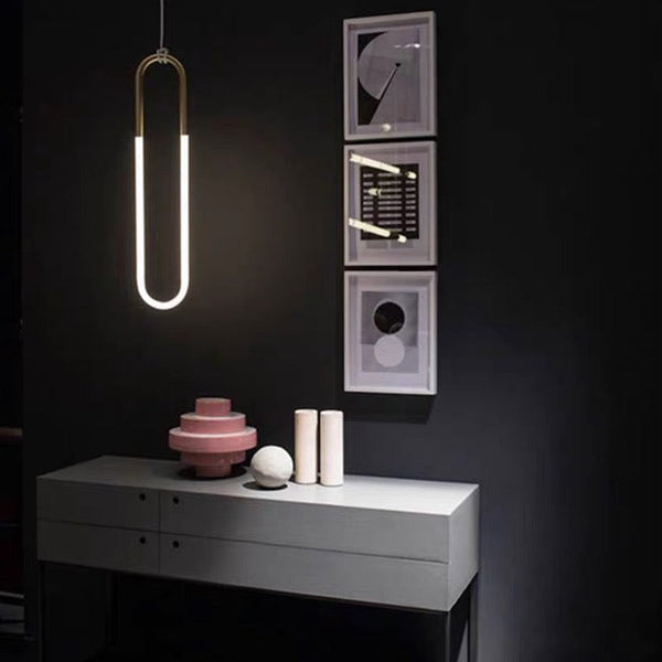 Modern pendant light fixture in a dark room with decorative items on a white console table.